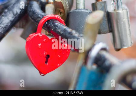 Heart-shaped love padlock with drops of rain in close-up view. Stock Photo