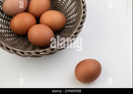Closeup of fresh brown eggs in Easter basket over white background. View from above Stock Photo