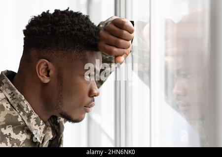 Pensive african american soldier looking through window at home Stock Photo