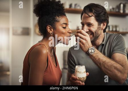 And there we go. Cropped shot of an affectionate middle aged man feeding his wife dessert in their kitchen at home. Stock Photo