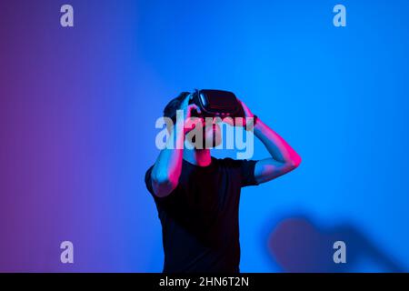 Metaverse and virtual reality concept. European bearded man in vr glasses exploring a virtual world while using a virtual reality headset. Stock Photo