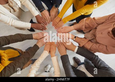 Motivated business people with their hands form circle that symbolizes unity and teamwork. Stock Photo