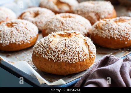 Freshly baked sesame seeded bagels on a baking tray. Close up. Stock Photo