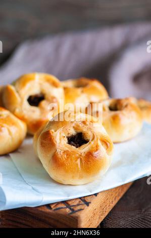 Middle Asian authentic baked meat hand pies  - belyash or samsa served on baking paper on wooden background. Stock Photo
