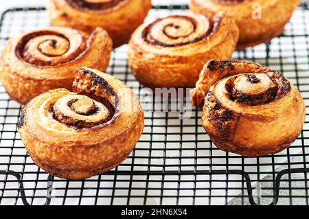 Aromatic homemade yeasty buns with cinnamon on a cooling rack. Close up. Stock Photo