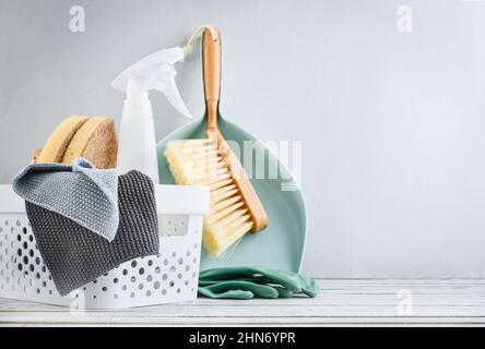 Set of cleaning supplies in blue color in plastic basket on blue background Stock Photo