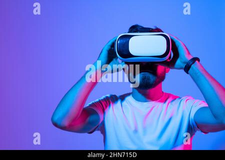 Closeup of young man developer wearing virtual reality goggles in modern studio workspace and working on a new perspective project. Stock Photo