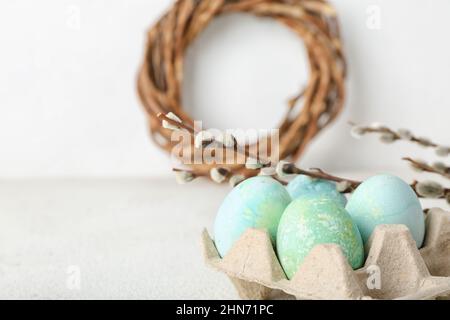 Holder with painted Easter eggs, pussy willow and figurine of bunny on ...