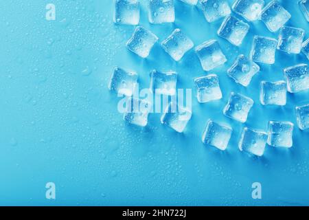 Ice cubes with water drops scattered on a blue background, top view ...