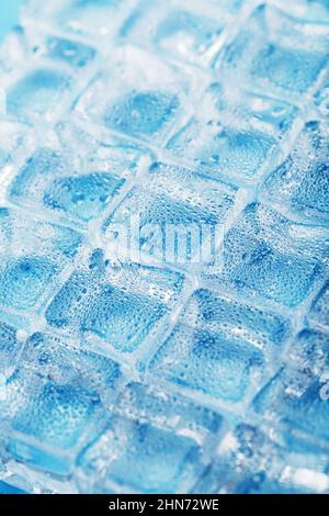 Many frosty and refreshing ice cubes with drops on a blue background. Refreshing drinks in hot weather Stock Photo