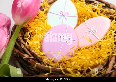 Nest with tasty Easter cookies and flowers on table, closeup Stock Photo