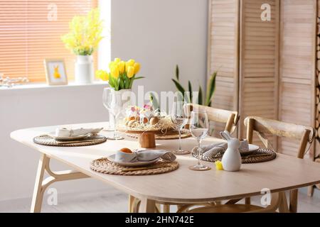 Festive dinnerware on table served for Easter celebration in room Stock Photo