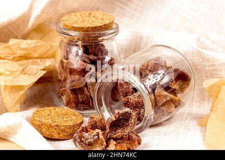 Traditional Japanese hoshigaki dried persimmon fruit snack slices in glass jars on light background. Stock Photo