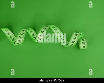 Green tape measure on the green background Stock Photo