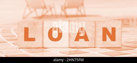 The LOAN sign on a wooden blocks on relaxed beach background. Business concept. Stock Photo