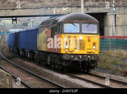 Colas Rail liveried class 56 grids diesel-electric loco number 56302 on the WCML passing through Carnforth with freight train on 14th February 2022. Stock Photo