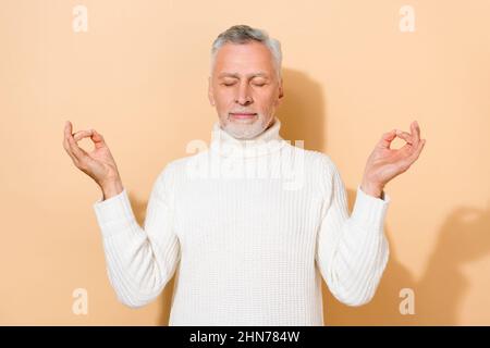 Portrait of attractive calm dreamy grey-haired man meditating resting hobby isolated over beige pastel color background Stock Photo