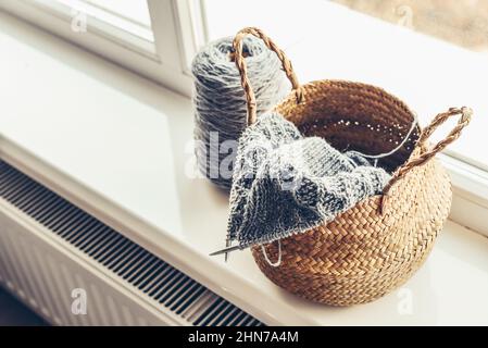 Wicker basket with knitting in progress on windowsill at home Stock Photo
