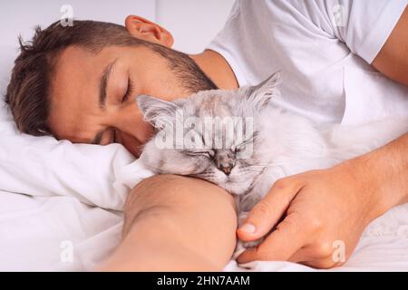 Man sleeping with cat. Lovely cat and owner. Love and trust between people and pets Stock Photo