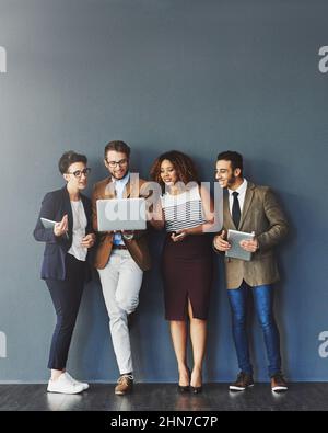 Staying connected for better productivity. Studio shot of a group of businesspeople using wireless technology together while standing in line against Stock Photo