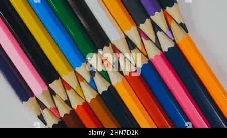 Many colored pencils are arranged around the edges of the image as a frame. In the center is an empty background with space for text. Mock up with copy space. Stock Photo