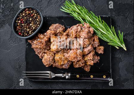 Stewed lamb and beef meat on a marble board. Black background. Top view Stock Photo