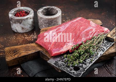Alternative raw flap flank beef meat steak on butcher board. Dark background. Top view Stock Photo