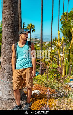 Portrait of stylish student in California with palm trees in the background during a sunny colorful day. Stock Photo