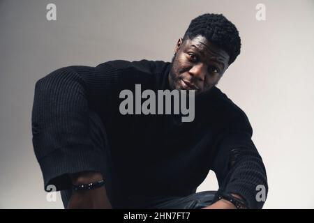 Afroamerican with resigned expression sitting looking at the camera white background - medium shot. High-quality photo Stock Photo