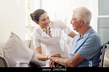 Shes always there with a helping hand. Shot of a caregiver helping a senior man in a wheelchair at home. Stock Photo