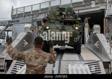 U.S. Army Soldiers assigned to America’s First Corps, maneuver a Stryker combat vehicle off United States Naval Ship City of Bismarck while conducting roll on-roll off training at Naval Base Guam, Feb. 9, 2022. Members of America’s First Corps deployed from Joint Base Lewis-McChord to Guam to conduct a training exercise that enhances readiness, showcases joint interoperability and exercises distributed mission command in the Pacific. (U.S. Army photo by Spc. Jailene Bautista, 5th Mobile Public Affairs Detachment) Stock Photo