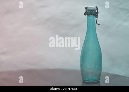 Empty vintage green glass bottle with ceramic lid and wire stopper on the table. Soft focus. Toned. Stock Photo