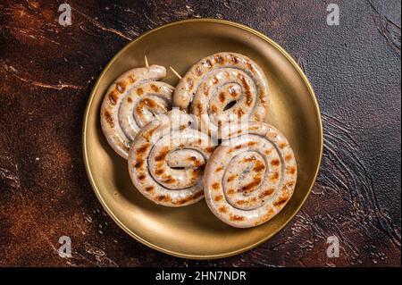 Bavarian Roasted spiral pork meat sausages with herbs. Dark background. Top view Stock Photo