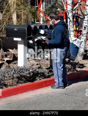 An American mailman or letter carrier delivers mail to a row of mailboxes in Santa Fe, New Mexico. Stock Photo