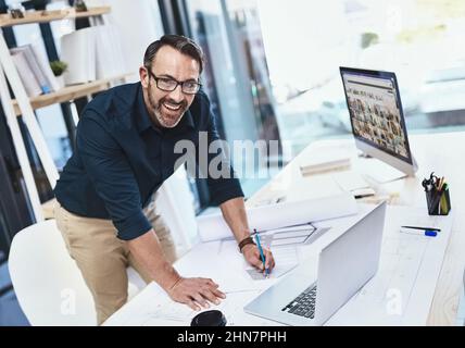 Im so inspired by the internet. Shot of a mature male architect working on his laptop. Stock Photo