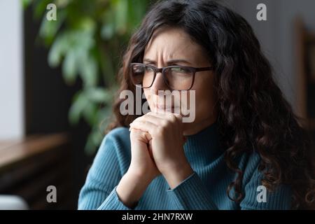 Young worried female employee in glasses feeling anxious, irritable or depressed at workplace Stock Photo