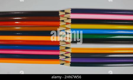 Many colored pencils are arranged around the edges of the image as a frame. In the center is an empty background with space for text. Mock up with copy space. Stock Photo