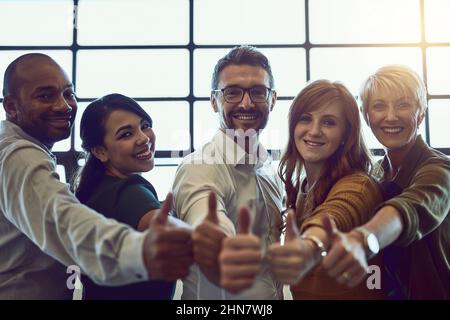 Thats a 10 out of 10 from us. Portrait of a team of colleagues giving a thumbs up in a modern office. Stock Photo