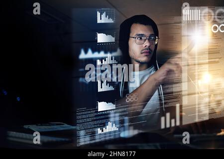 Theres no code he cant crack. Shot of a young hacker cracking a computer code in the dark. Stock Photo