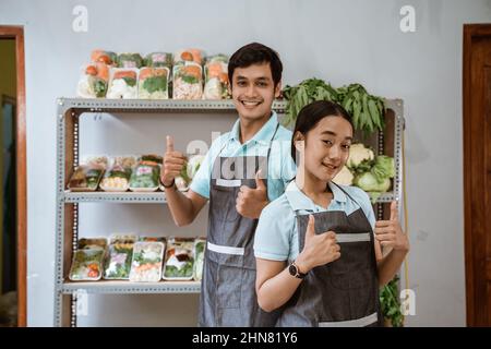 Smiling female and male shop assistants with thumbs up Stock Photo