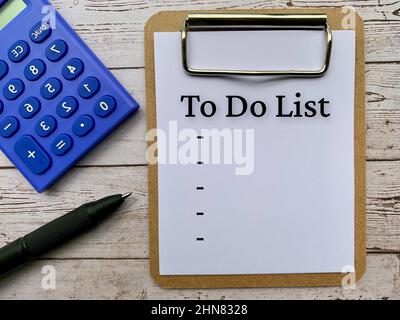 Top view of text on notepad - To do list. With calculator, pen and wooden desk background. Business concept. Stock Photo