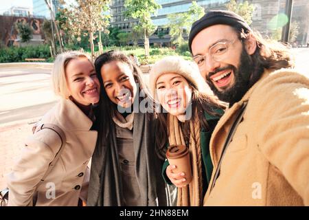 Group of business colleagues smiling while taking a selfie together outdoors during a break from work. Stock Photo