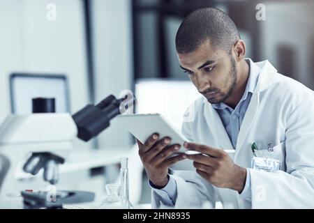 Using his tablet for research purposes. Shot of a scientist recording his findings on a digital tablet. Stock Photo