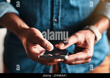 My customers can text me too. Cropped shot of an unrecognizable businessman standing alone in his home office and texting on his cellphone. Stock Photo