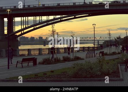 Novosibirsk, Siberia, Russia - 09.10.2019: Novosibirsk embankment in the evening at sunset. Arched road bridge, railway bridge over the Ob river in th Stock Photo