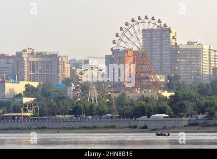 Novosibirsk, Siberia, Russia-06.10.2019: Novosibirsk embankment in the early morning. Green Park on the river embankment with Ferris wheels and attrac Stock Photo
