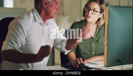 Editing their work to perfect their top standards. 4k video of two colleagues working late on a computer in an office. Stock Photo