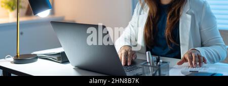 Overwork Concept The female working in the office and typing something on the computer laptop. Stock Photo