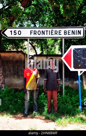Burkinabe men standing under a direction road sign in South Eastern Burkina Faso. Stock Photo
