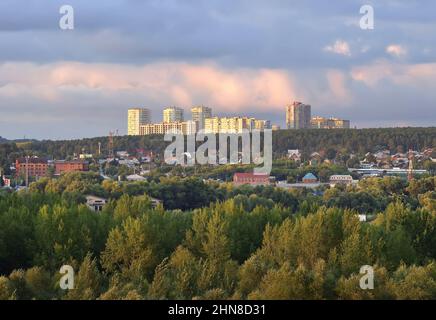 Novosibirsk, Siberia, Russia - 08.20.2020: Apartment buildings on a hilltop in pink light under a cloudy sky Stock Photo